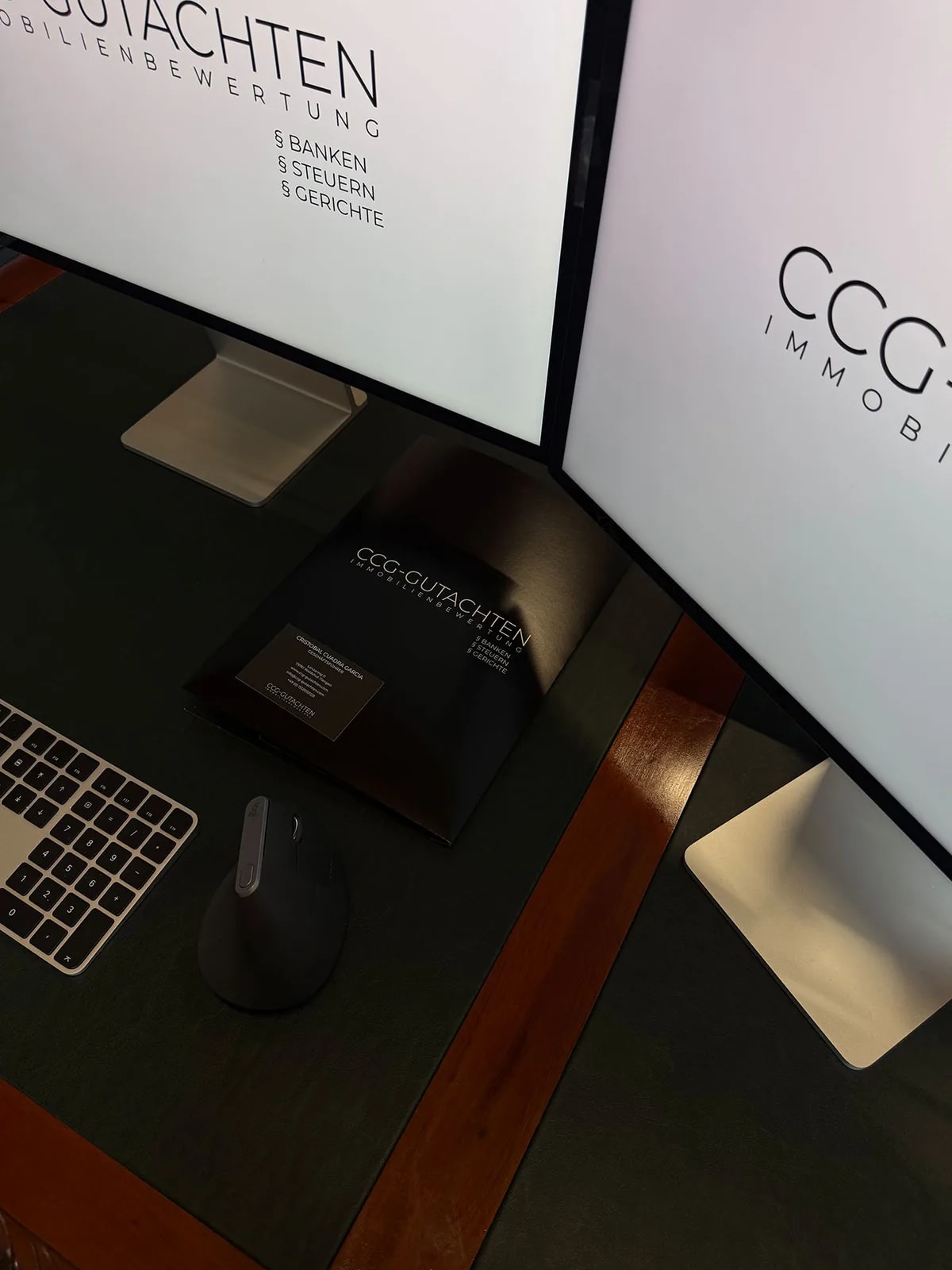 Schreibtisch mit zwei Bildschirmen und Unterlagen zur Immobilienbewertung bei CCG-Gutachten